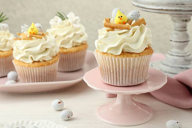 istock Tasty Easter cupcakes with vanilla cream on light wooden table 2248152659