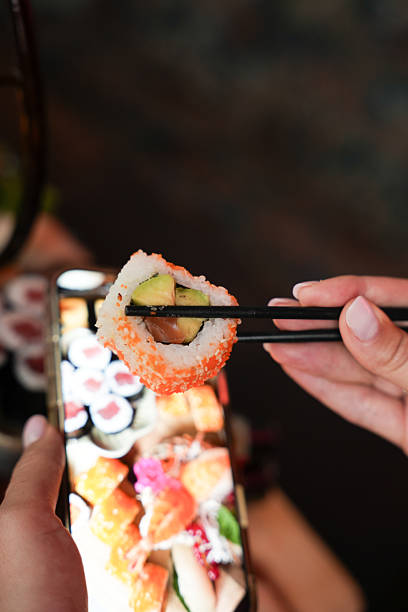istock Sushi Roll with Avocado and Salmon in Chopsticks 2248153372