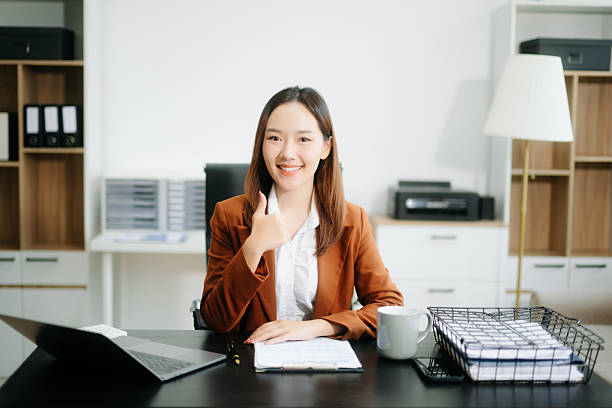 istock Young beautiful woman typing on tablet and laptop while sitting at the working white table 2248153780