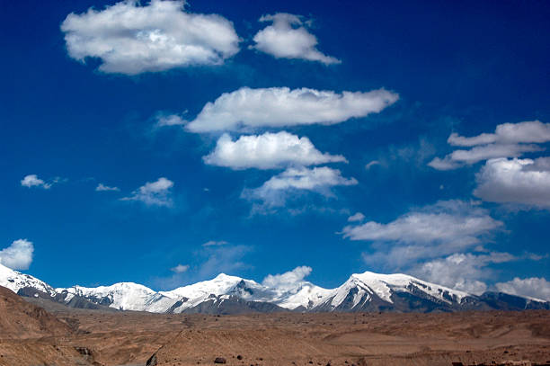 A picturesque scene of snowy mountains under a vivid blue sky with scattered clouds, showcasing natural beauty.