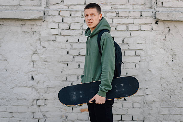 istock Young man holding skateboard near brick wall 2248157830