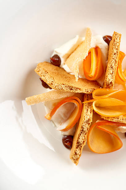 istock A minimalist and abstract dessert featuring crispy pastry shards and bright orange fruit or caramel ribbons, served with a creamy element in a deep white bowl. 2248159272