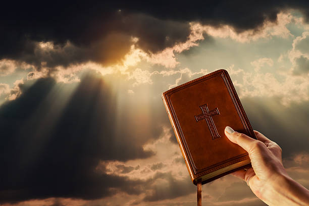 istock Hand holding Bible toward dramatic heavenly sky 2248160974