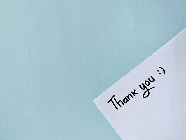 istock Thank you message hand written on white paper on blue background 2248162444