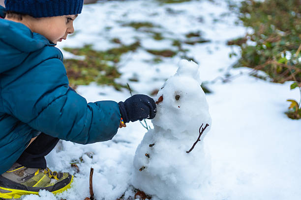 istock Child building snowman outdoors on snowy winter day 2248163520