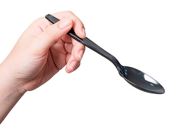 istock Female hand holding a black plastic spoon isolated on white background. 2248164488