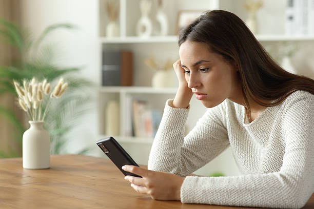 istock Bored woman sitting at home checking smart phone 2248164580