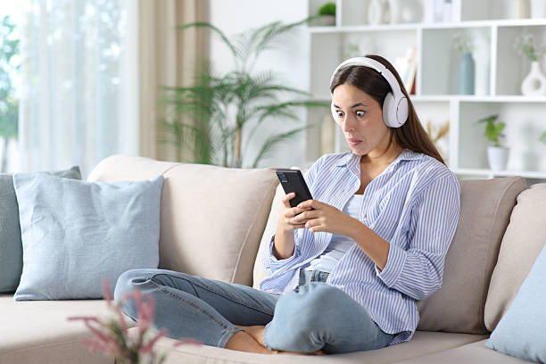 istock Perplexed woman wearing headphone watching media on phone 2248164713