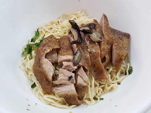 Thai local noodle dish featuring egg noodle soup served with wontons, white radish, roasted pork slices, and vegetables. Popular thai local food.