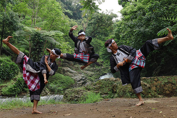 Pencak Silat Martial Artists Showcasing Their Moves Near a Waterfall, Symbolizing Indonesian Culture with Traditional Costume