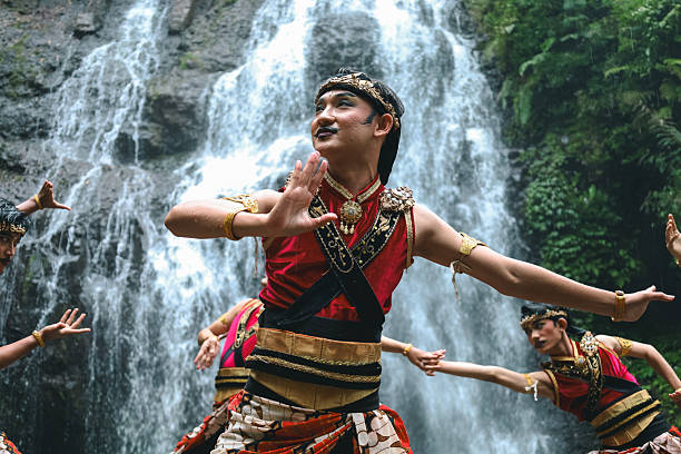 Portrait of Indonesian Dancers Performing Traditional Choreography Against Stunning Waterfall Backdrop for Cultural Celebration