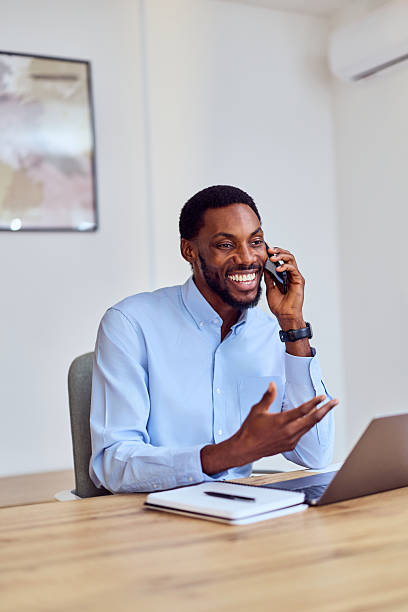 istock Smiling Male Professional On Phone Call At Office Desk With Laptop And Notebook 2248169420
