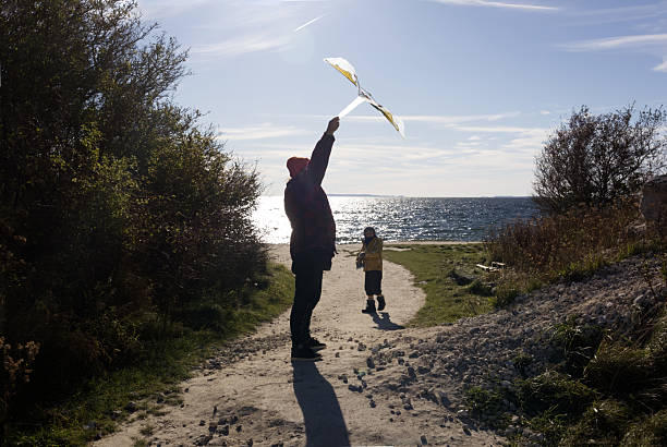 Father and Son Flying a Kite on a Sunny Coastal Path Overlooking the Sparkling Sea
