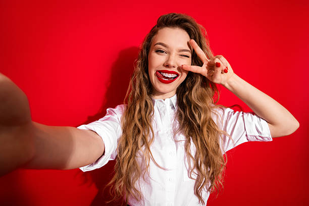 istock Smiling young woman making a peace gesture against a bright red background embracing happiness and modern lifestyle 2248171737
