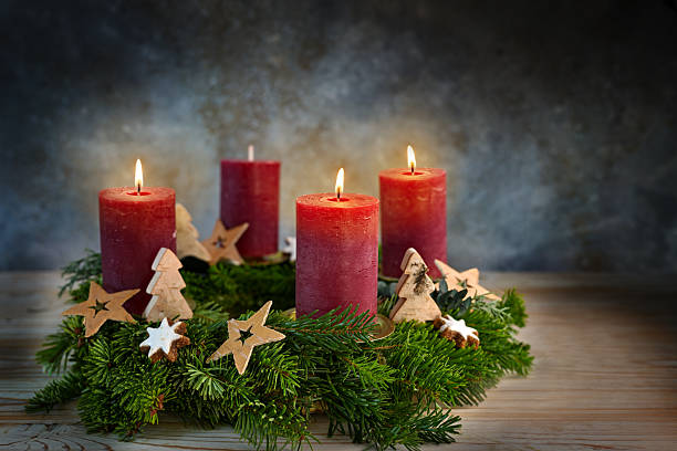istock Four red candles on an Advent wreath, three are lit for the third advent, small stars, cinnamon cookies and wooden trees as Christmas decoration, bluish background, copy space 2248171848