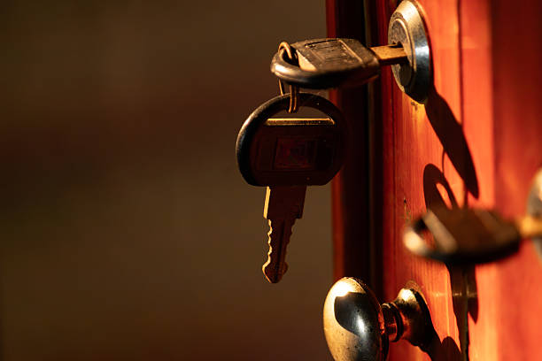 Close up of keys hanging from a lock on a red door illuminated by sunset light, safety concept.