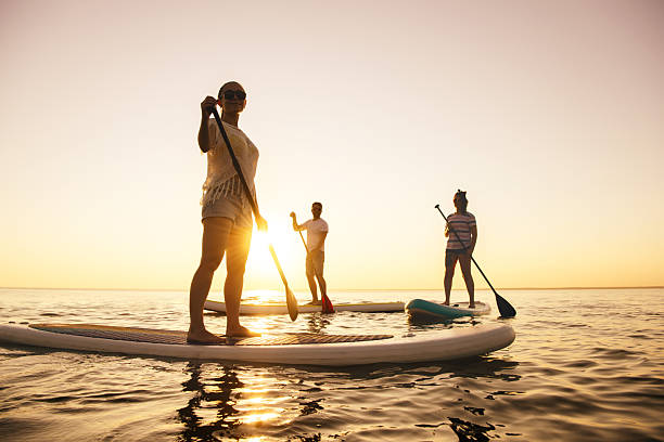 istock Three tourists are walking on sup boards at sunset lake 2248173800