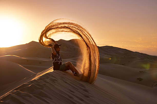 istock Happy tourist sits on sandy dune and throw sand 2248173814