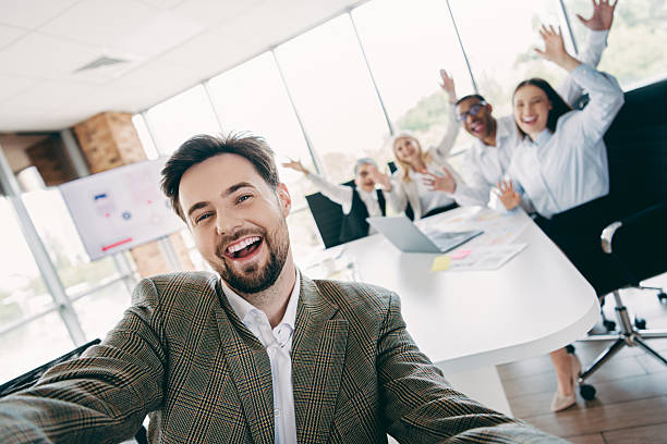 istock Group of professionals in a modern office taking selfie and celebrating teamwork, collaboration, and workplace unity 2248173944