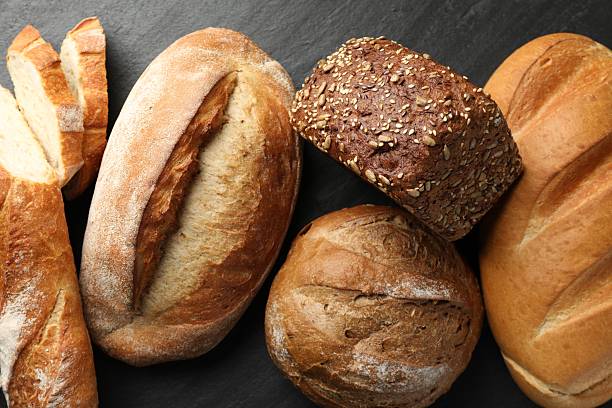 istock Loafs of different bread on black background, flat lay 2248174131