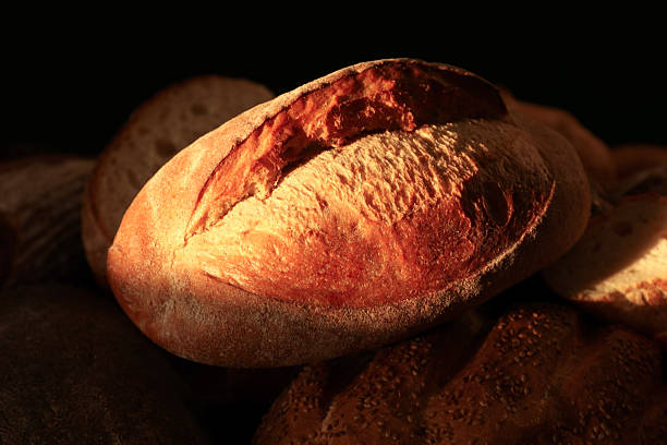 Loaf of crusty bread on dark background, closeup