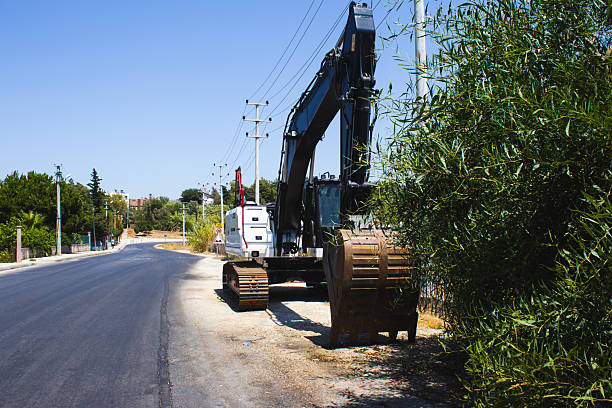 medium-distance shot focusing on the lower section of a large, tracked excavator parked on a rough dirt and gravel road in bright daylight