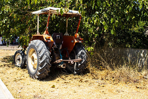 view shot of an aged, orange-red agricultural tractor parked outdoors