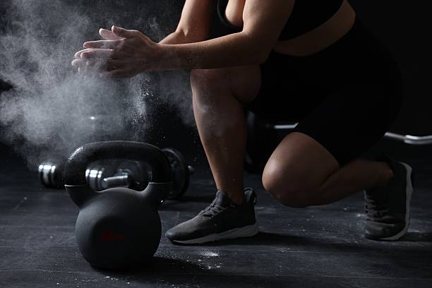 istock Woman clapping hands with talcum powder before training with kettlebell on black background, closeup 2248175821