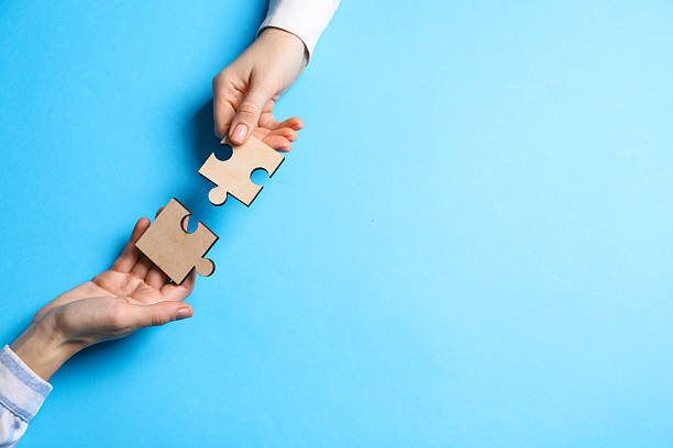 istock Business strategy and teamwork concept. Partners putting puzzle pieces together on light blue background, top view. Space for text 2248176417