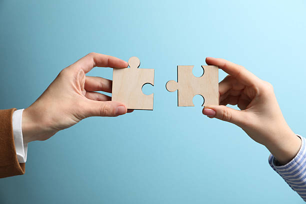 istock Business strategy and teamwork concept. Partners putting puzzle pieces together on light blue background, closeup 2248176462