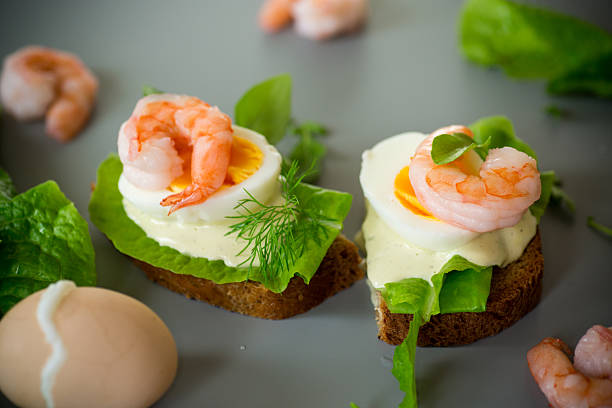 Sandwich with egg and shrimp on gray background from above.