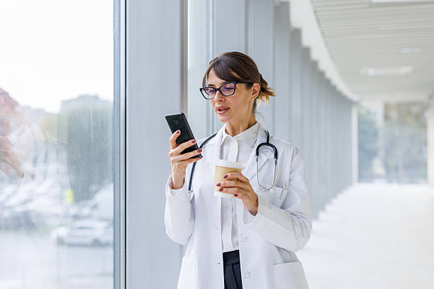 istock Female doctor checking smartphone taking coffee break 2248177475