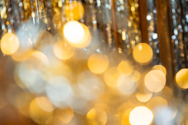 Holographic festive background with shiny tinsel and glitter. Gold and silver bokeh create a New Year and Christmas celebration mood. Perfect metallic, colorful holiday texture.