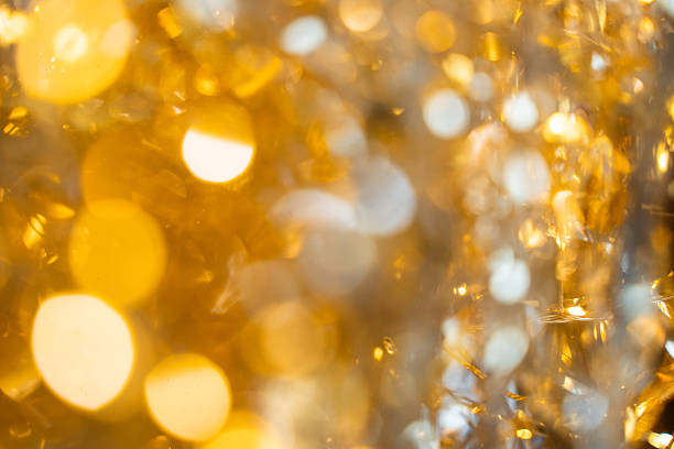 Holographic festive background with shiny tinsel and glitter. Gold and silver bokeh create a New Year and Christmas celebration mood. Perfect metallic, colorful holiday texture.