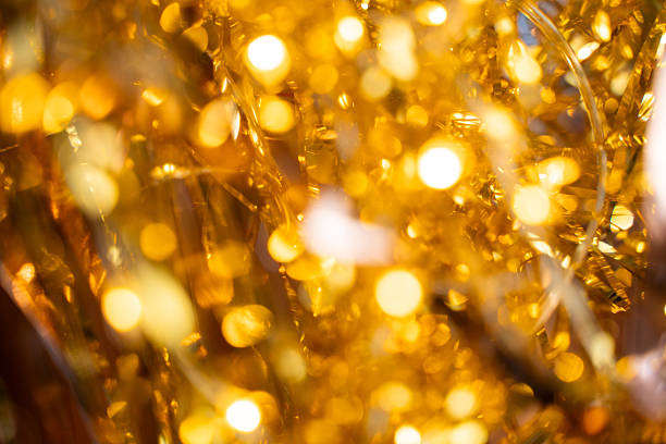 Holographic festive background with shiny tinsel and glitter. Gold and silver bokeh create a New Year and Christmas celebration mood. Perfect metallic, colorful holiday texture.