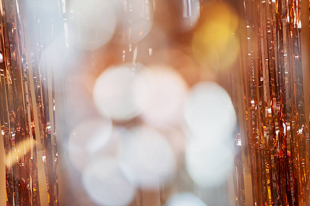 Holographic festive background with shiny tinsel and glitter. Gold and silver bokeh create a New Year and Christmas celebration mood. Perfect metallic, colorful holiday texture.