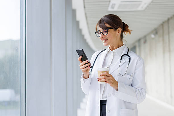 istock Female doctor using phone and drinking coffee on break 2248188044