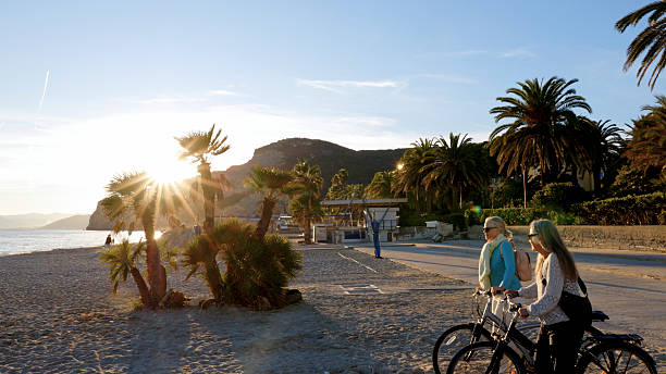 istock Mature women push bicycles onto beach at sunset 2248191167