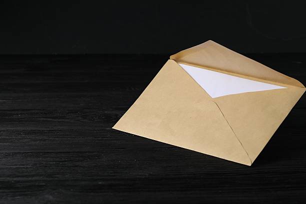 istock Kraft paper envelope with letter on black wooden table. Mockup for design 2248191484