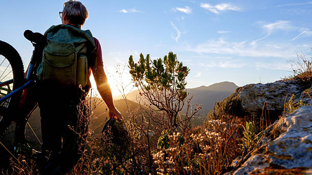 istock Mountain biker carries e-bike on mountain at sunset 2248192894