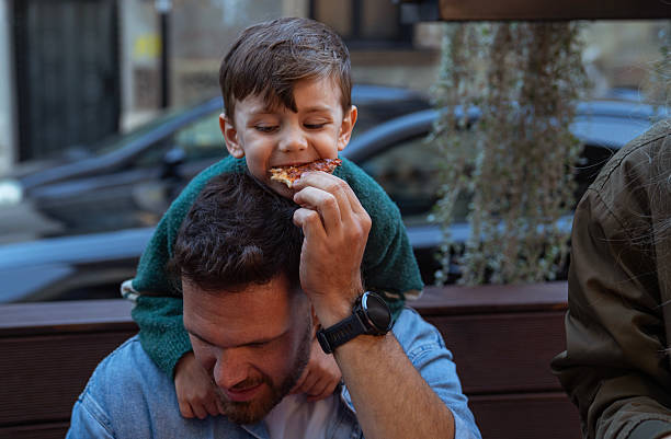 istock Father sharing a slice of pizza with his son 2248196027