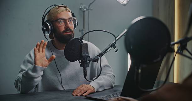 istock Podcast Host With Open Laptop Listening to Guest, Both Using Headphones and High End Microphones 2248198345