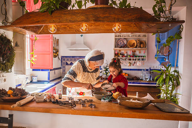 Grandma and granddaughter baking christmas cookies in rustic kitchen