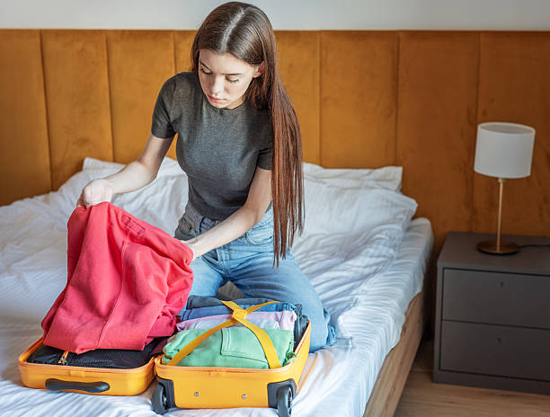 istock Young woman packing suitcase for upcoming trip on bed 2248201884