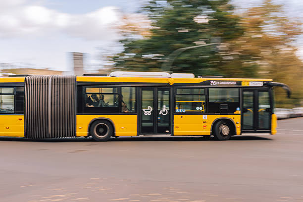 Berlin, Germany – October 11, 2025: A BVG articulated bus moves through city traffic, captured with motion blur as it travels along a wide urban street.