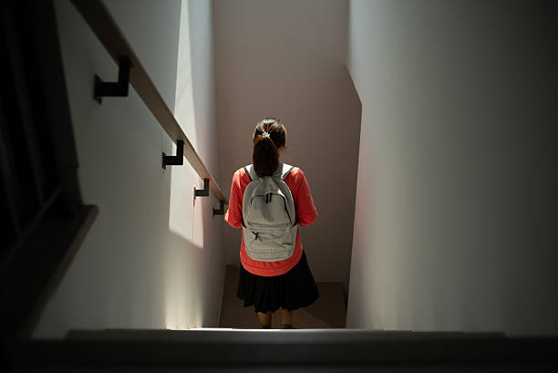 Asian young woman student walking down stairs on their way to school.