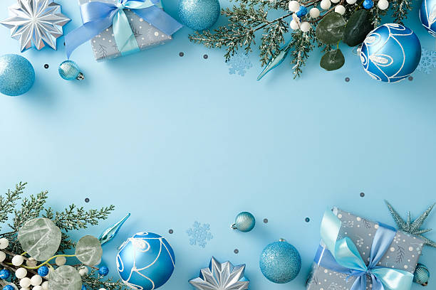 istock Light blue background framed by Christmas ornaments and two beautifully wrapped gift boxes with ribbons 2248204750
