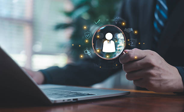 istock A person using a magnifying glass to review user icons on a laptop screen, representing recruitment, candidate selection, and digital HR analysis. human resource management, recruit leadership 2248205556