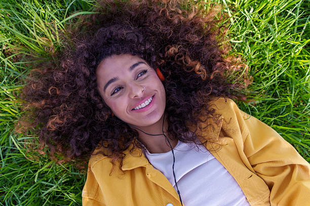 istock Young woman enjoying music while relaxing on grass 2248207102