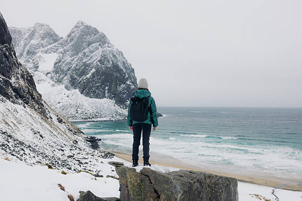 istock Female With Backpack Admiring Dramatic Winter Mountain Beach From Above on Lofoten Islands 2248208221